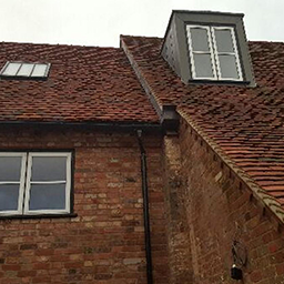 red brick house and roof with a window on the roof