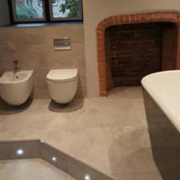 a tiled bathroom with floor lighting and a open fire place