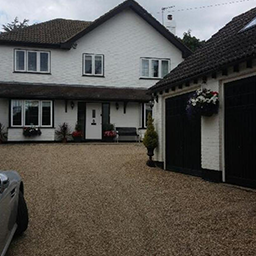 gravel driveway to a white house