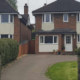 A cobbled drive way and red brick house