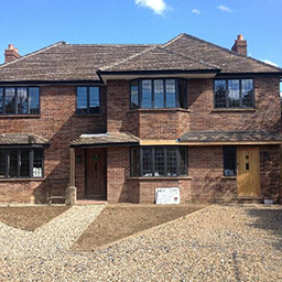 a large red brick house with a shingle driveway