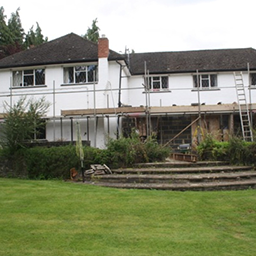 a garden and a white house with scaffolding